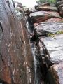 El agua cae sobre una pared de rodeno